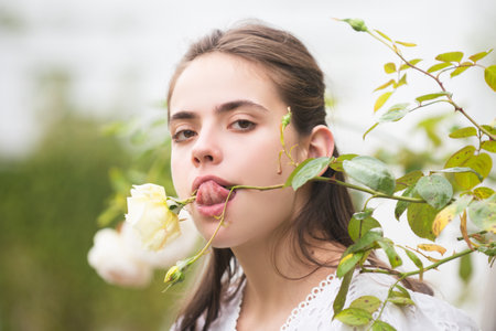 Spring girl. Young woman enjoying blooming spring garden. The concept of youth, love, fashion and lifestyle. Beautiful young girl in the park and a flowering park roses.の写真素材