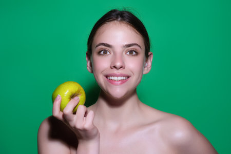 Woman bitting tasty apple. Woman eating apple, studio portrait. Morning breakfast. Woman with healthy teeth holding apples on isolated background. Healthy teeth. Dentistry, dentist and dental care.の写真素材