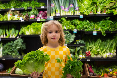 Child with lettuce chard vegetables. Shopping with kids. Kid buying fruit in supermarket. Little boy buy fresh vegetables in grocery store. Kid choosing vegetables. Healthy food.の写真素材