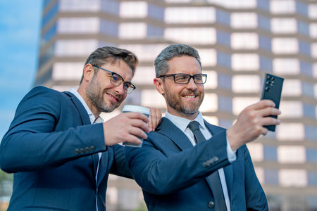 Two business men using phone outdoor. Planning of two business teams strategy. Two business men teams strategic approach was effective in achieving their goals.の写真素材