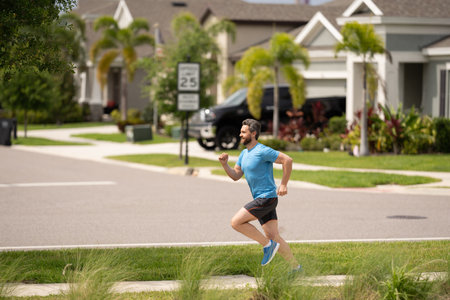 Male jogger running in park. Full length portrait of an athletic young man running outdoor. Sport and healthy lifestyle concept. Fitness man running in the city, male runner outdoors against the urban street.の写真素材