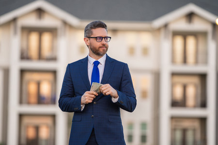 Successful rich business man with dollar cash money outdoor. Real estate investment. Profit and financial success. Employer or lawyer in suit with money outdoor. Rich client, customer or owner.の写真素材