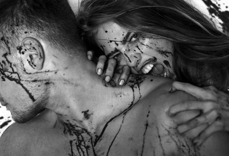 A bloody couple, a vampire girl bites a muscular man by the neck. A terrible Halloween episode, the girl bites her boyfriend by the neck, with blood on her face and blood lust.の写真素材