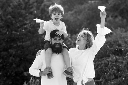 Father mother and son camping. Dad mom and his child son are playing on sky background. Happy child with parents playing with toy wings against summer sky background.の写真素材