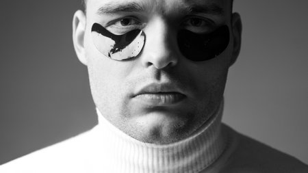 Man with black eye patches close up face. Beauty treatment. Skin care. Metrosexual concept. Focused treatments for under eye area. Minimizes puffiness and reduce dark circles. Eye patches for menの写真素材