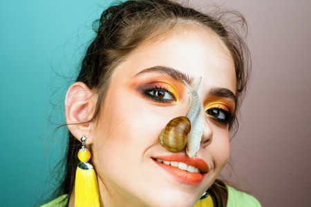 Healing mucus. Having fun with adorable snail. Cosmetics and snail mucus. Cosmetology beauty procedure. Girl fashionable makeup face and cute snail. Skin care. Massage with snail. Skincare repairingの写真素材