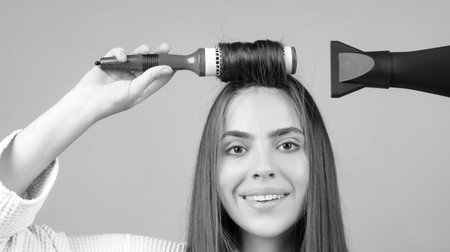 Woman combing hair, dryer hair with hairdryer. Portrait of female model with a comb brushing hair. Girl with with hair dryer, beauty.の写真素材