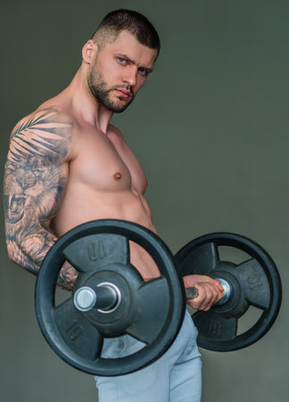 Muscular man workout in the gym. Athletic man having weight training in gym. Handsome man with strong muscles workout in the gym. Portrait of sexy muscular male with dumbbells. Bodybuilder exercise.の写真素材