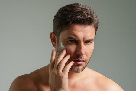 Man care of skin. Charming man with perfect soft skin. Male beauty and skincare concept. Man cosmetic, skin treatment. Morning hygiene. Mens cosmetics and wellness. Skincare. Man with cream on face.の写真素材