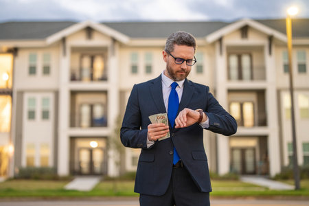 Man in suit holding cash money in dollar banknotes outdoor. Portrait of businessman with bunch of dollar banknotes. Dollar money concept. Career wealth business. Insurance agent.の写真素材