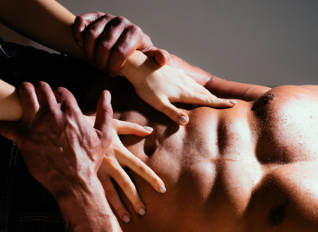 Sexy muscular naked man and female hands on naked body. Woman hands on a sexy man torso. Womans hands embracing man with naked muscular torso. Female hands on a male body.の写真素材