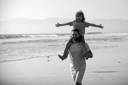 Father giving son ride on back outside. Little boy kid with daddy carrying him on shoulders. Dad and child enjoying outdoor. Lifestyle and family vacation, happiness men concept.の写真素材