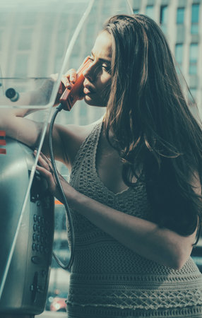 Oldstyled city. Vintage concept. Woman with payphone. Communication. Old fashion town.の写真素材