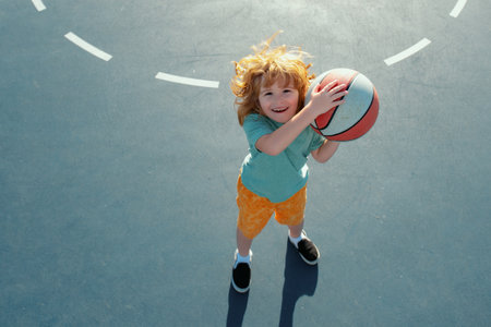 Cute smiling boy plays basketball. Kid shooting basketball ball and playing basketball. Healthy children lifestyle, outdoor on playground.の写真素材