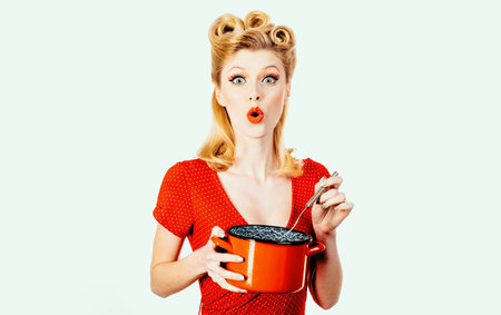 Beautiful blonde pinup woman housewife holding pan. Studio shot over white background isolated.