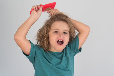 Daily hair care routine. Little child boy combing hair, isolated background.の写真素材
