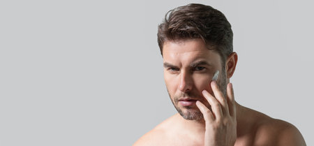 Banner with copy space of man touching chin and skin. Handsome man touching face in front of the mirror in bath. Perfect skin. Man cosmetic, skin treatment. Hygiene and skin care male face.の写真素材