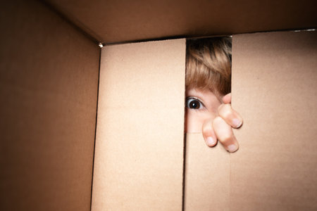 Excited child boy looking into the box, shipping cardboard box. Close up eyes looking.の写真素材