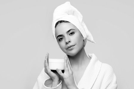 Face beauty care. Portrait of beautiful woman with facial cream in hand. Sexy female with fresh...