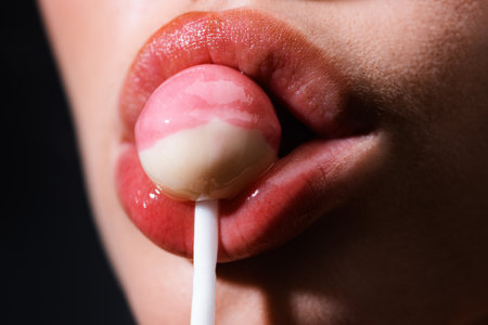 Close up lips sucking a lolipop, lollypop. Woman with lollipop in mouth. Red lips, sweats lolly pop.の写真素材