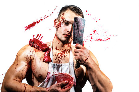 At butcher shop. Butcher chopping red meat. Handsome man cutting raw steak with butcher axe in...