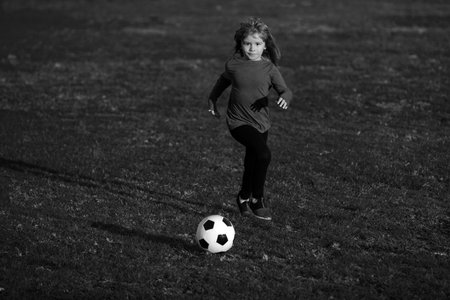 Young soccer player. Cute boy kicking soccer ball. School kids playing football in a field.の写真素材