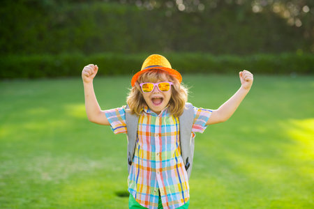 Fashion summer kids portrait. Lifestyle portrait of cute kid outdoors. Summer kids outdoor portrait. Excited kids in hat and summer sunglasses. Summer kid outdoor portrait. Little winner gesture win.の写真素材