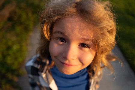 Funny kids emotions. Outdoor close up portrait of a cute little child playing outdoor. Portrait of pretty little kids face outside.の写真素材