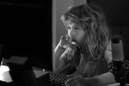 Child playing computer games or studying on pc computer. Kid gamer on night neon lighting. Child using computer technology in home.の写真素材