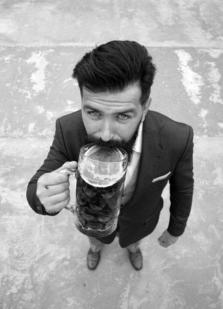 Full length, wide angle. Funny man drinking beer from a glass mug.