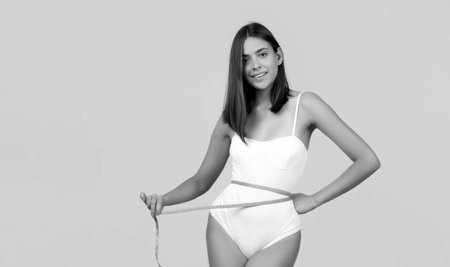 Young girl measuring her waist. Female fit slim body. Trained belly with measuring tape.の写真素材