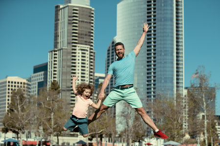 Excited father and son jumping on urban city background. Concept of friendly family.の写真素材