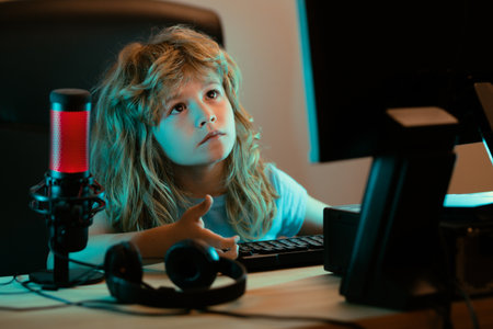 Child with pc computer at night. A pretty child learns a lesson using a desktop computer at home. Home education.の写真素材