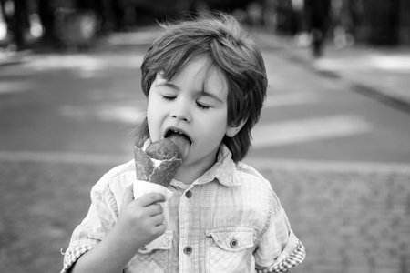 Kids junk food. Child eating ice cream outdoor. Delicious summer snacks.の写真素材