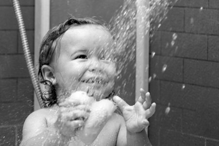 Bathing smiling baby. Happy kid with soap foam on head. Funny child in shower.