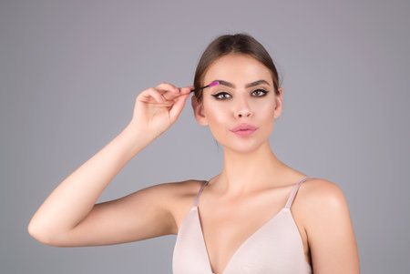 Female model shaping brown eyebrows. Woman eye with beautiful eyebrows. Perfect shaped brow, eyelashes with brow gel brush. Paint eyebrows.の写真素材