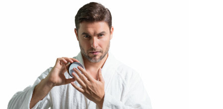 Male model applying cosmetic cream on face. Facial treatment. Beauty portrait of man applying face...