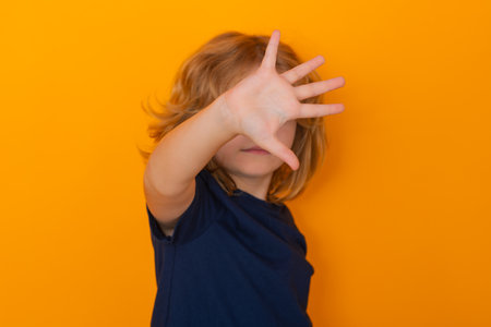 Child making stop gesture on isolated studio background. Kid showing warning symbol, hand sign no. Kids protection, bullying, abuse and violence concept.の写真素材