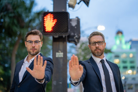 Businessmen doing stop sing with hand. Warning expression with negative and serious gesture. Stop...