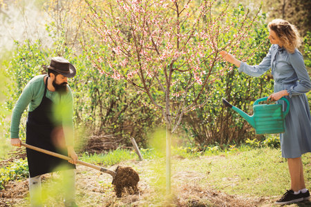 Portrait of a young happy couple in yard during spring season. Happy Couple Farmers working with spud on spring field.の写真素材