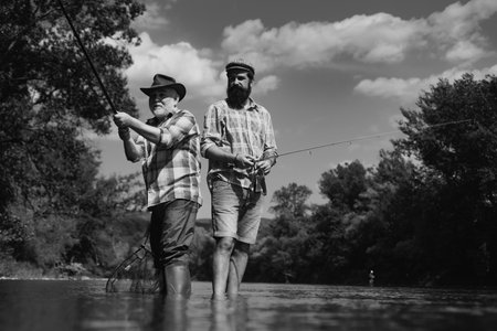 Father and mature son fisherman fishing with a fishing rod on river.