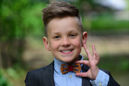 Little fashion portrait of kid boy in suit and bow tie. Outdoor closeup portrait of funny kids face....