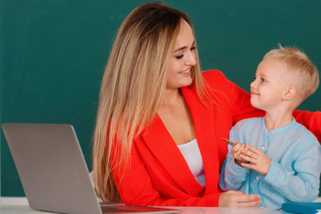 Mother and son together using computer laptop. School child learning education online lesson. Teacher helps school kids to learn lesson.の写真素材