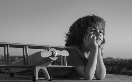 Kids playing with vintage wooden airplane outdoors. Portrait of children 6 year old against summer sky background. Travel and freedom concept.の写真素材