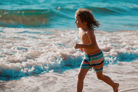 Child running through water close to shore along the sea beach. A boy runs along the sea coast. Rest of children on summer vacation.の写真素材
