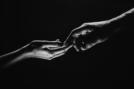 Two hands reaching toward. Tenderness, tendet touch hands in black background. Romantic touch with fingers, love. Hand creation of adam.の写真素材