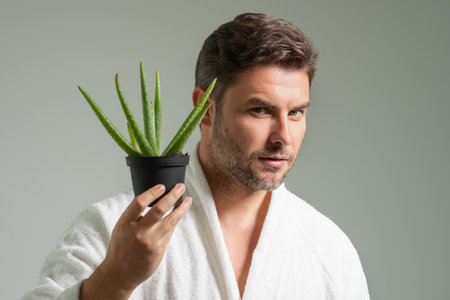 Clean face, face care, facials concept. Middle aged man with aloe vera isolated on studio background. Aloe vera for cosmetics skin mask. Facial mask with aloe vera. Spa, dermatology, wellness and facial treatment.の写真素材