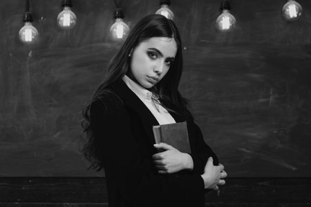 Portrait of girl teenager in school. Young teenager with school books. Back to school. Beautiful female holding her books in auditorium. Back to school and happy time.の写真素材