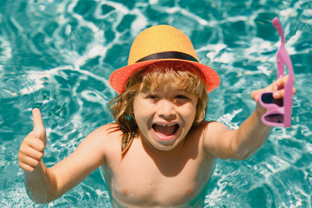 Kid boy relaxing in pool. Child swimming in water pool. Summer kids activity, watersports. Summer vacation with children. Child enjoying summer in the water in the swimmingpool.の写真素材