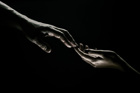 Hands gesturing on black background. Giving a helping hand. Support and help, salvation. Hands of two people at the time of rescue. Romantic touch with fingers, love. Hand creation of adam.の写真素材